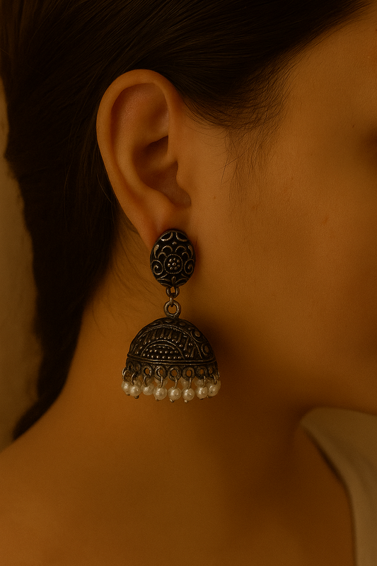 Close-up of an ear wearing a decorative earring with pearl-like beads.