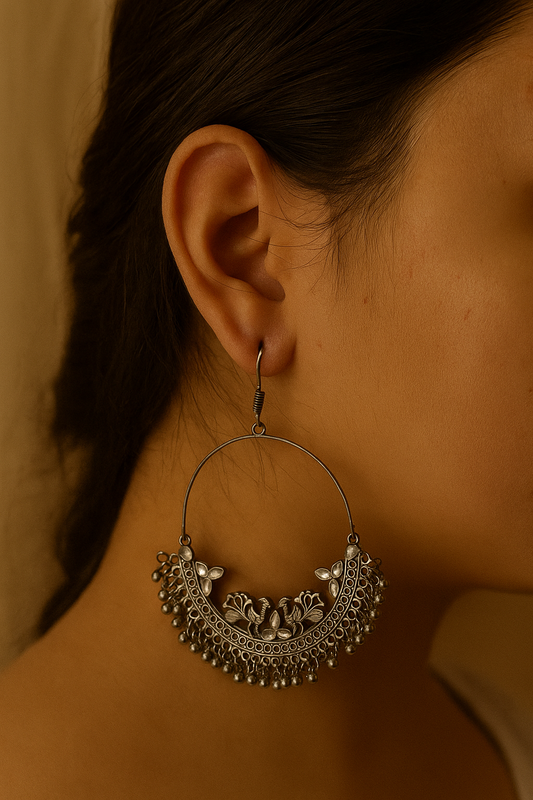 Close-up of a person wearing an ornate silver earring against a neutral background